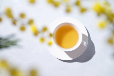 Beyaz bir masanın üzerinde sarı mimoza çiçekleri olan bir bahar buketi. 8 Mart 'ın konsepti, mutlu kadınlar günü. Üst görünüm ve kopyalama alanı