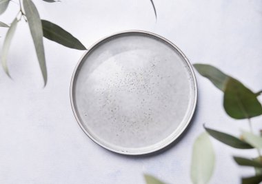 Arka planda okaliptüs dalları olan boş bir tabak. Kutlama masası. Üst görünüm ve kopyalanacak yer.