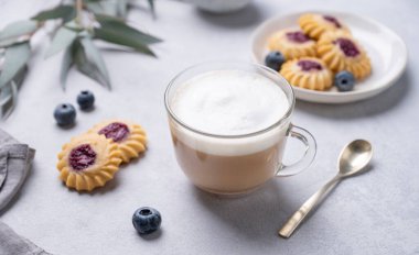 Kapuçino ya da süt köpüklü latte ev yapımı çilekli kurabiye ve okaliptüs dallı hafif bir arka planda yabanmersini. Bahar sabahı kahvaltısı hariç.. 