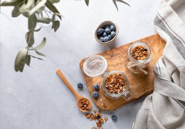 Fındıklı ev yapımı tahıl gevreği ve hafif arka planda bir kavanozda taze yaban mersini. Kahvaltıda sağlıklı vejetaryen müsli. Metin için üst görünüm ve boş alan.