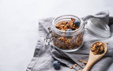 Fındıklı ev yapımı tahıl gevreği ve peçeteli bir kavanozda taze yaban mersini. Kahvaltıda sağlıklı vejetaryen müsli. Metin için boş alan.