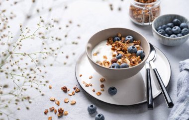 Sağlıklı bir yoğurt kahvaltısı, granola ve çiçekli taze yaban mersini konsepti. Ev yapımı diyet ve protein yiyeceği. Boşluğu kopyala.