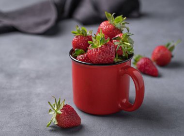 Kırmızı bardakta sulu çilekler ve peçeteli koyu bir arka plan. Çiftlik olgun, sağlıklı böğürtlenler. Metin için boş alan.