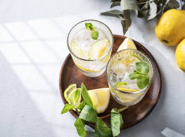 Taze limon, limon, nane ve buzlu limonata. Hafif arka planda gölgeli narenciyeli mojito kokteyli. Yaz soğuk içecekler konsepti. Üst görünüm ve kopyalama alanı.