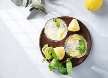 Taze limon, limon, nane ve buzlu limonata. Hafif arka planda gölgeli narenciyeli mojito kokteyli. Yaz soğuk içecekler konsepti. Üst görünüm ve kopyalama alanı.