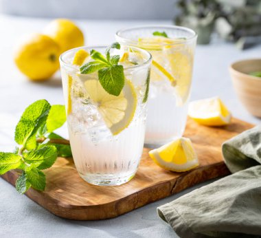 Taze limon, limon, nane ve buzlu limonata. Hafif arka planda gölgeli narenciyeli mojito kokteyli. Yaz soğuk içecekler konsepti. Ön görünüm.