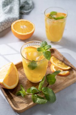 Taze sıkılmış meyve suyu taze portakallı, naneli ve buzlu metalik tüp ve gölgeli bir bardakta. Kahvaltıda sağlıklı narenciye arınması..