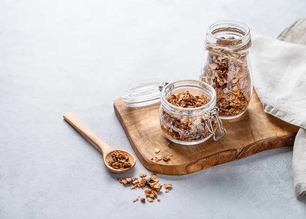 stock image Homemade baked granola with nuts and raisins in a jar on a light background. Healthy vegetarian muesli for breakfast. Free space for text.