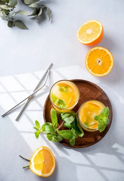 用新鲜的橙子 薄荷和冰块 用金属管和阴影在淡淡的背景下 在杯子中新鲜挤压果汁 健康的柑橘排毒早餐喝 顶部视图和复制空间 — 图库照片