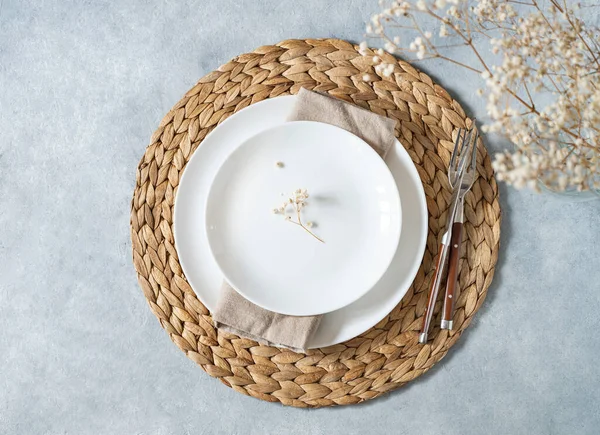 Masa, minimalist tarzda beyaz plakalı ve mavi arka planda bir buket çigila. Üst görünüm ve kopyalama alanı.