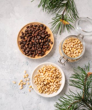 Kavanozda çam fıstığı ve arka planda çam iğnesi dallarıyla dolu bir kavanoz. Doğal, organik ve sağlıklı abur cubur kavramı. Üst görünüm.