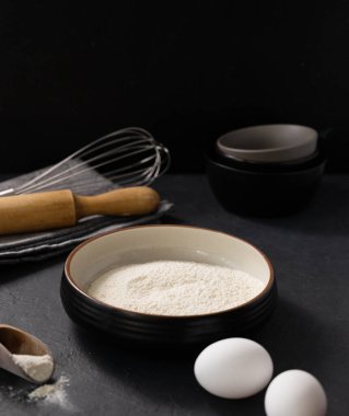 Organik pişirme malzemeleri. Un, yumurta ve siyah arka planda merdane. Ev yapımı ve sağlıklı yemek kavramı. Metin için boş alan.