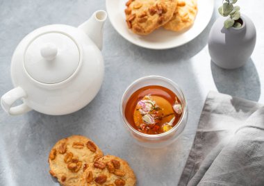 Bir fincan bitki çayı, çaydanlık ve sabah gölgesi olan mavi arka planda ev yapımı kurabiyeler. Kahvaltıda içki konsepti. Üst görünüm.