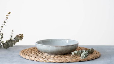 Seramik plakalı masa ayarları ve mavi arka planda okaliptüs dalları. Asgari tarz konsept. Ön görünüm ve boşluk kopyala.