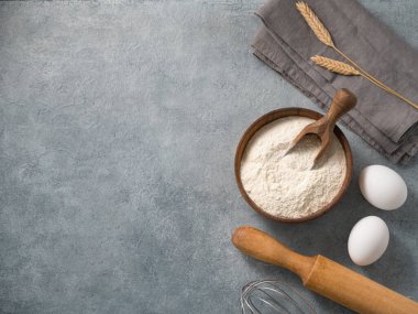 Mavi arka planda pişirme, buğday unu, yumurta, merdane ve mutfak tekstili malzemeleri. Ev yapımı sağlıklı gıda konsepti. Üst görünüm ve kopyalama alanı.
