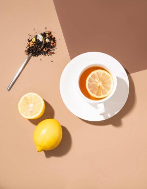 Kahverengi arka planda koyu gölgeli limonlu bir fincan çay. Yiyecek ve içecek konsepti. Üst görünüm ve kopyalama alanı.