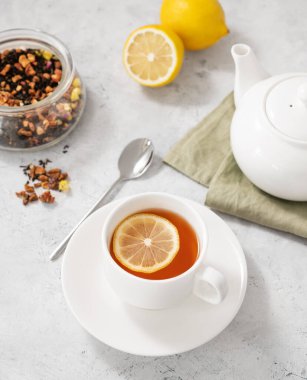 Limonlu bir fincan bitki çayı ve arka planda hafif bir çaydanlık. Kahvaltı için sağlıklı ve detoks içeceği konsepti. Üst görünüm.