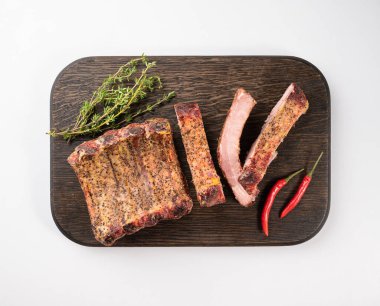 Izgara bbq domuz kaburgası, kırmızı biber ve ahşap bir tahtada taze kekik, beyaz izole bir arka plan. Üst görünüm ve kopyalama alanı.