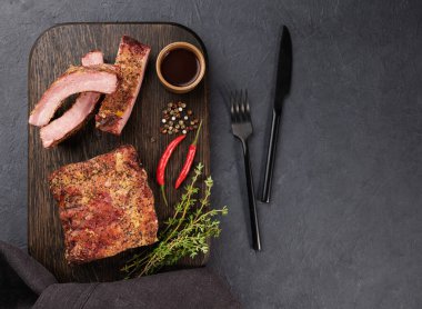 Izgara domuz kaburgası, bbq sosu, acı biber ve ahşap bir tahta üzerinde taze bitki. Üst görünüm ve kopyalama alanı.