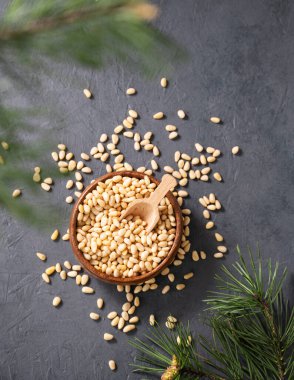 Bir kasede çam fıstığı ve arka planda bir çam iğnesi dalları. Doğal, organik ve sağlıklı abur cubur kavramı. Üst görünüm ve kopyalama alanı.