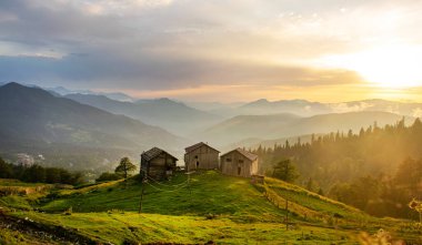 Gün batımında eski ahşap evleri ve güzel gökyüzü olan dağların ve dağ köyünün manzarası. Gürcistan 'da bir dağ köyünde akşam manzarası. Svaneti, Georgia.