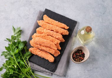 Balık fileto çubukları, çiğ, kaykay tahtasında maydanozla birlikte yağlı ve baharatlı. Diyet ve sağlıklı yiyecekler. Üst görünüm.