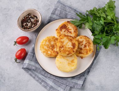 Patatesli kızarmış vejetaryen pirzolası, arka planda hafif bir tabakta taze otlar ve domateslerle birlikte. Lezzetli ev yapımı vejetaryen diyet yemekleri. Üst görünüm.