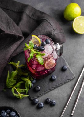 Böğürtlenli mojito ya da limonata, limon, nane ve buzlu ve peçete ve metal tüplü koyu bir zemin. Meyve ve böğürtlenden yapılan sağlıklı bir içecek. Üst görünüm.