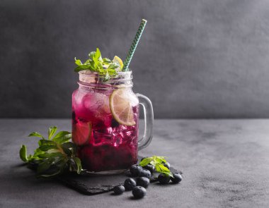 Böğürtlenli mojito ya da limonata, nane ve buzlu koyu bir arka planda. Meyve ve meyvelerden yapılan sağlıklı yaz alkolsüz içeceği. Metin için ön görünüm ve boş alan.