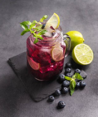 Böğürtlenli mojito ya da limonata, nane ve buzlu koyu bir arka planda. Meyve ve meyvelerden yapılan sağlıklı alkolsüz içecek. Üst görünüm.