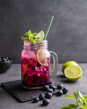 Böğürtlenli mojito ya da limonata, nane ve buzlu koyu bir arka planda. Meyve ve meyvelerden yapılan sağlıklı yaz alkolsüz içeceği. Ön görünüm.