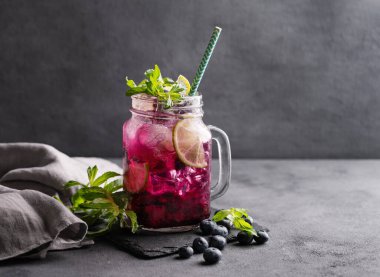 Böğürtlenli mojito ya da limonata, nane ve buzlu koyu bir arka planda. Meyve ve meyvelerden yapılan sağlıklı yaz alkolsüz içeceği. Ön görünüm ve boşluk kopyala.