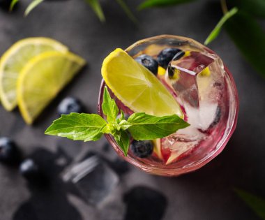 Yabanmersinli mojito ya da limonlu, buzlu ve naneli limonata koyu bir arka planda, meyveli ve meyveli bir bardakta. Yaz tazeleyici içecek konsepti. Üst görünüm.