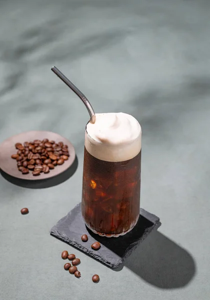 Ledová Káva Pěnou Sklenici Černém Prkně Tmavozeleném Pozadí Kávovými Zrny — Stock fotografie