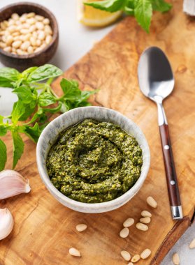 Geleneksel İtalyan pesto yeşil fesleğen, çam fıstığı, peynir ve zeytinyağı ile ahşap tahtaya yakın. Spagetti ya da bruschetta için klasik bir sos. Lezzetli ev yapımı vejetaryen yemeği. Üst görünüm.