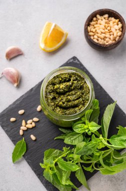 Arka planda yeşil fesleğen, çam fıstığı, peynir ve zeytinyağlı geleneksel İtalyan pesto tablosu. Spagetti ya da bruschetta için klasik bir sos. Üst görünüm.