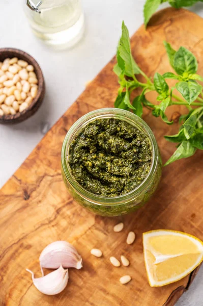 Geleneksel İtalyan pesto 'su yeşil fesleğen, çam fıstığı, peynir ve zeytinyağı ile ahşap tahtaya yakın. Spagetti ya da bruschetta için klasik bir sos. Lezzetli ev yapımı vejetaryen yemeği. Üst görünüm.