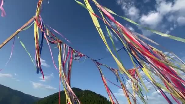 五彩斑斓的彩带或花环在夏日阳光明媚 乌云密布的蓝天里迎风飘扬 退去瑜伽节 — 图库视频影像