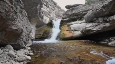 Güneşli bir yaz gününde, kayalar ve berrak suyla dolu bir dağ geçidinde güzel bir şelale. Dağıstan, Rusya
