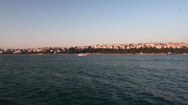 Gün batımında denizden İstanbul 'a manzara. Şehrin çevresinde eski ve yeni evleri olan kıyı şeridi. Yaz panoramik manzarası. Türkiye.