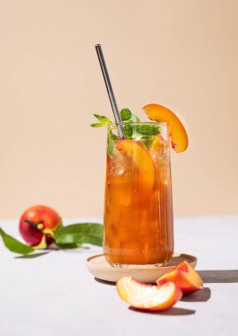 Şeftalili buz ve nane çayı. Vejetaryen ev yapımı soğuk yaz içeceği açık arka planda uzun bir bardakta taze meyve ve gölgelerle. Metin için ön görünüm ve boş alan.