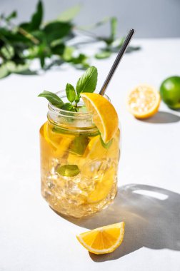 Limonata ya da taze limon, nane ve buzlu soğuk çay. Hafif arka planda taze meyve ve gölgelerle narenciye kokteyli. Ev yapımı sağlıklı ve detoks içeceği konsepti. 