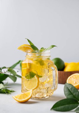 Limonata ya da taze limon, nane ve buzlu soğuk çay. Hafif bir arka planda taze meyveli narenciye mojito kokteyli. Ev yapımı sağlıklı ve detoks içeceği konsepti. Ön görünüm.