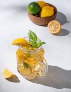 Limonata ya da taze limon, nane ve buzlu soğuk çay. Hafif arka planda taze meyve ve gölgelerle narenciye kokteyli. Ev yapımı sağlıklı ve detoks içeceği konsepti