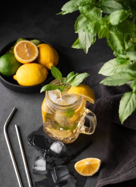 Limonata, limon, nane ve buzlu bir kavanozda taze limon. Limonlu mojito kokteyli ya da koyu bir arka planda soğuk çay. Ev yapımı sağlıklı ve detoks içeceği konsepti. Üst görünüm.