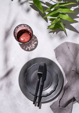 Karanlık gri tabaklar ve gölgeli açık arkaplanda okaliptüs dalları olan bir kutlama için cam kaplı şenlik masası. Restoran menüsü konsepti. Üst görünüm.