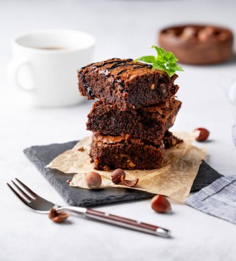 Nane, fındık ve karamelli çikolatalı kek yığını. Kabartma kağıdında, hafif bir arka planda, bir fincan kahveyle birlikte. Kahvaltıda lezzetli ve ev yapımı hamur işleri konsepti.. 