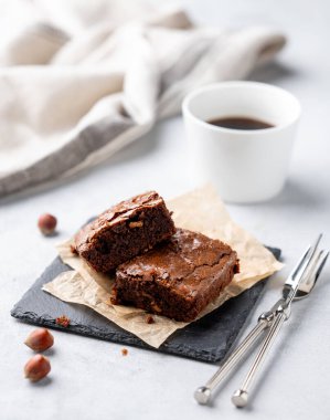 Fındıklı çikolatalı browni parçaları ve bir fincan kahveyle kabartma kağıdının üzerinde tuzlu karamel. Lezzetli ve tatlı ev yapımı fırın ürünleri konsepti. Vejetaryen tatlı..