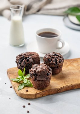 Tahta bir tahtanın üzerinde çikolatalı kekler ve arka planda bir fincan kahve ve sütle birlikte nane şekeri. Kahvaltı için ev yapımı sağlıklı yemek kavramı.. 
