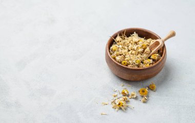 Arka planda ahşap bir kasede kurumuş papatya çayı. Sağlıklı yiyecek ve içecek konsepti. Bitkisel ve kuru otlu alternatif ilaçlar. Metin için boş alan.